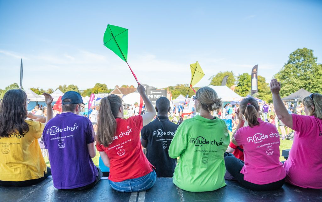 Choir members performing at an event holding kites