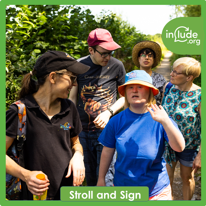 A photo of 5 people walking down a path in the countryside chatting and using hand gestures while talking 