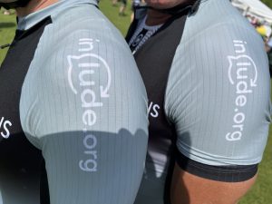 Close up of the sleeves of two people's cycling tops that have the Include.org logo on them