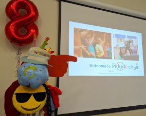The Include Choir hatstand wearing a Happy Birthday hat next to an 8th Birthday baloon
