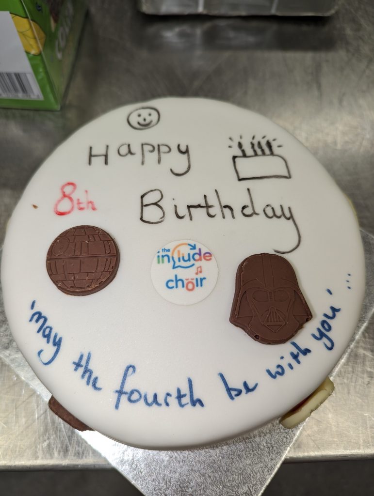 Birthday cake with icing and star wars chocolates on it with the words "May the 4th be with you"