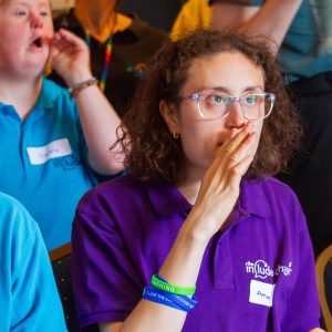 Amelia at The Include Choir singing and Makaton signing. she wears a purple top and glasses