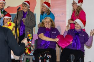 Members of The Include Choir performing in santa hats