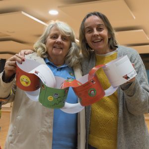 A paperchain with messages and stickers on it is made and held up between two Choir members
