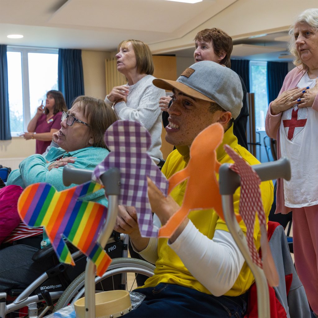 Members of The Include Choir in Epsom rehearse. They have an object of reference to represent friendship - it is a string of paper dolls.