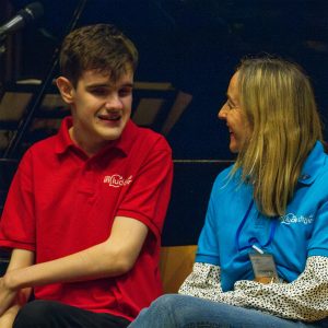 Harry and Include Choir Member and Charlotte an Include Choir Volunteer are wearing their Choir tshirts and talking to each other