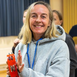 Volunteer Charlotte smiling and playing atambourine