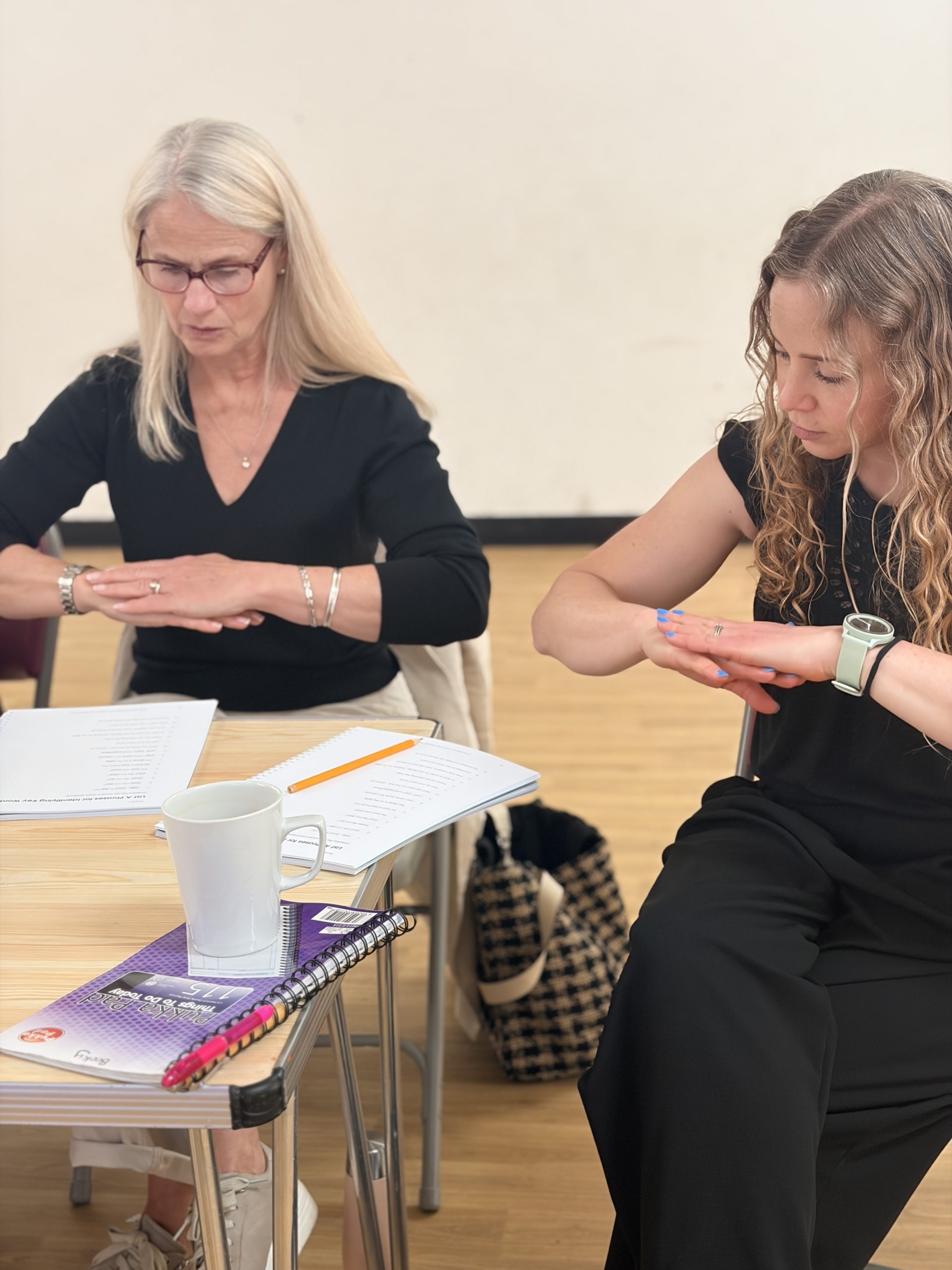 2 people practicing Makaton signs from their training manuals